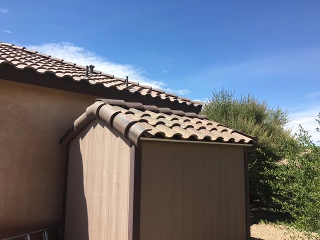 A house with a brown tiled roof set against a clear blue sky, showcasing a serene and picturesque scene.